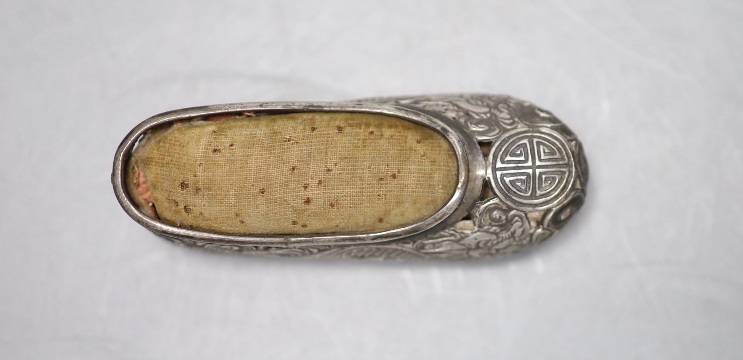 An early 20th century Chinese pierced white metal pin cushion, modelled as a shoe, maker KW, 81mm.